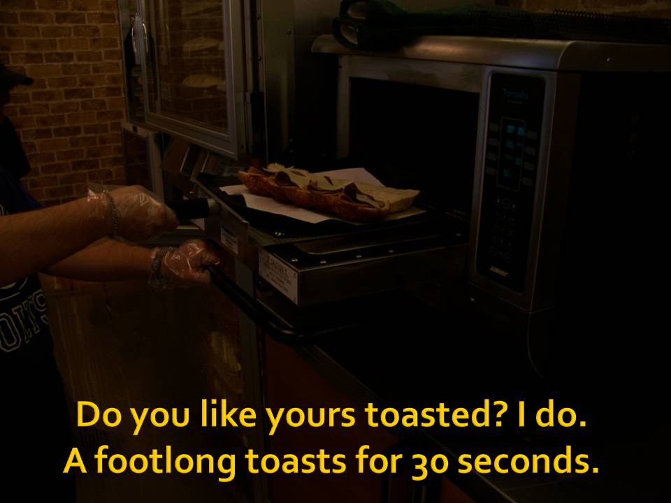 Person toasting a footlong sandwich in a toaster oven