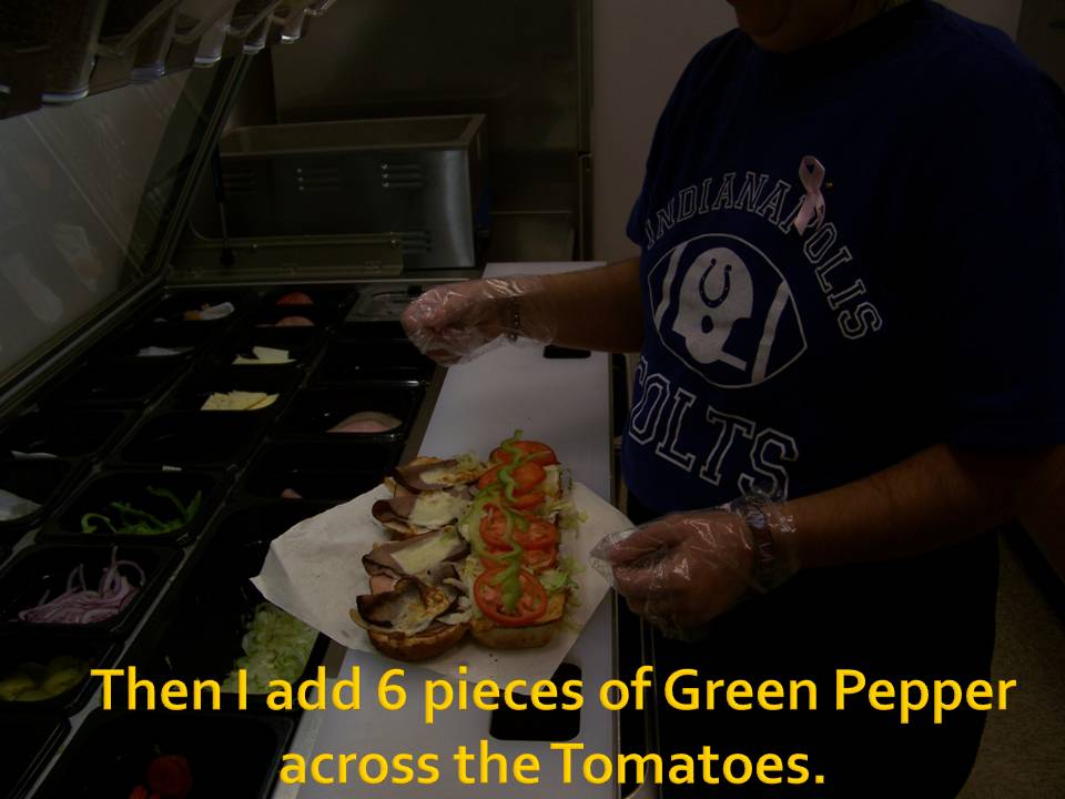 person making a sandwich with lettuce, tomato, and meat