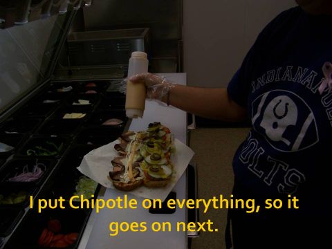 1989 Ford Bronco - Someone is adding sauce to a large sandwich at a food prep station.