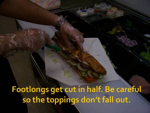 1989 Ford Bronco - A footlong sandwich is being cut in half, with care taken to prevent toppings from falling out.
