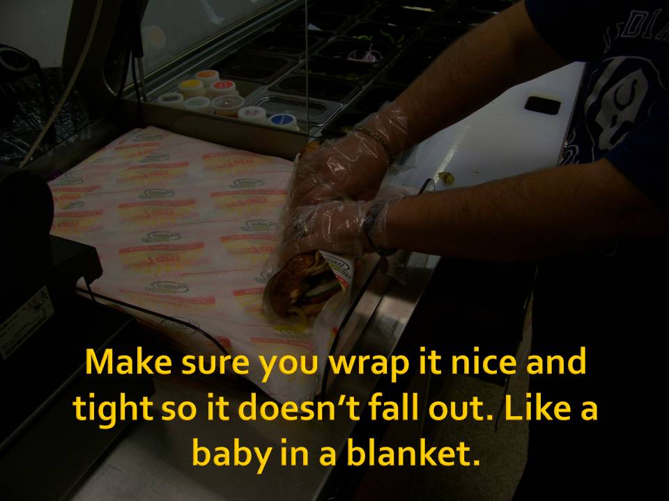 Person in gloves wrapping a sandwich on patterned paper