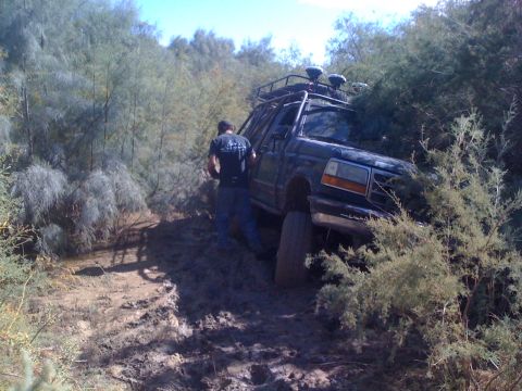 1989 Ford Bronco - A 1989 Ford Bronco is stuck in the mud, with a person standing beside it.