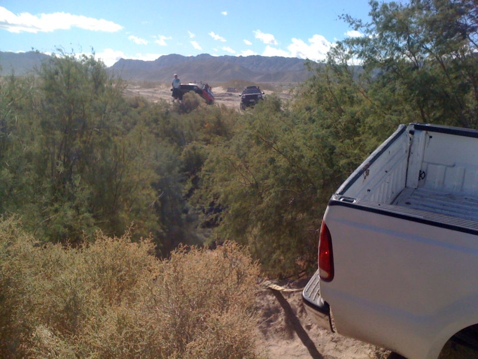 Pickup truck rear view with off-road vehicles in background desert landscape