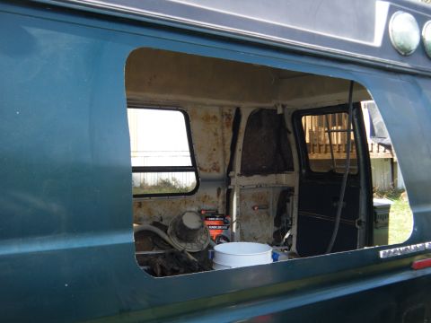 1981 Ford E350 - The interior of a van shows signs of wear and modification, with a large opening on the side.
