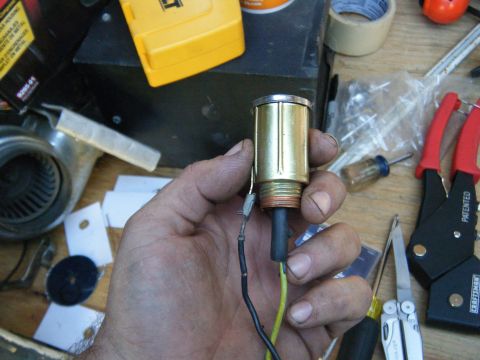 1981 Ford E350 - A person holds a brass cigarette lighter assembly, with wires extending from it, against a backdrop of various tools and parts.