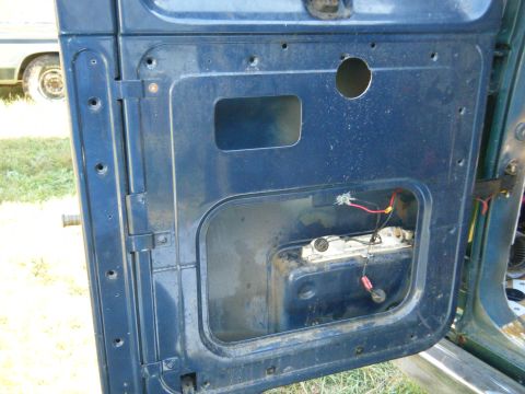 1981 Ford E350 - The interior of a blue van door shows exposed wiring and a large cutout for components.