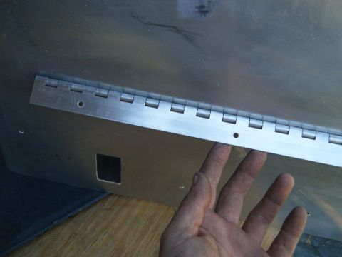 1981 Ford E350 - Hand touching a metal panel with a hinge and a square cutout.