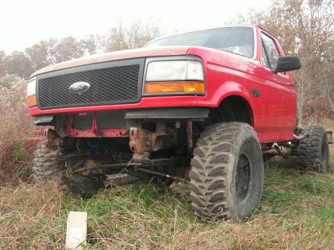 1995 Ford F-150 - This red 1995 Ford F-150 pickup features large off-road tires and a modified front end.