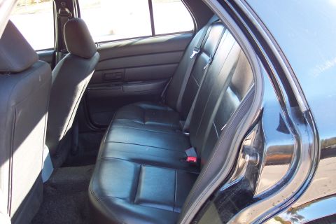 2001 Ford Crown Victoria - Rear interior view of a 2001 Ford Crown Victoria, showing the black leather seats and door panel.