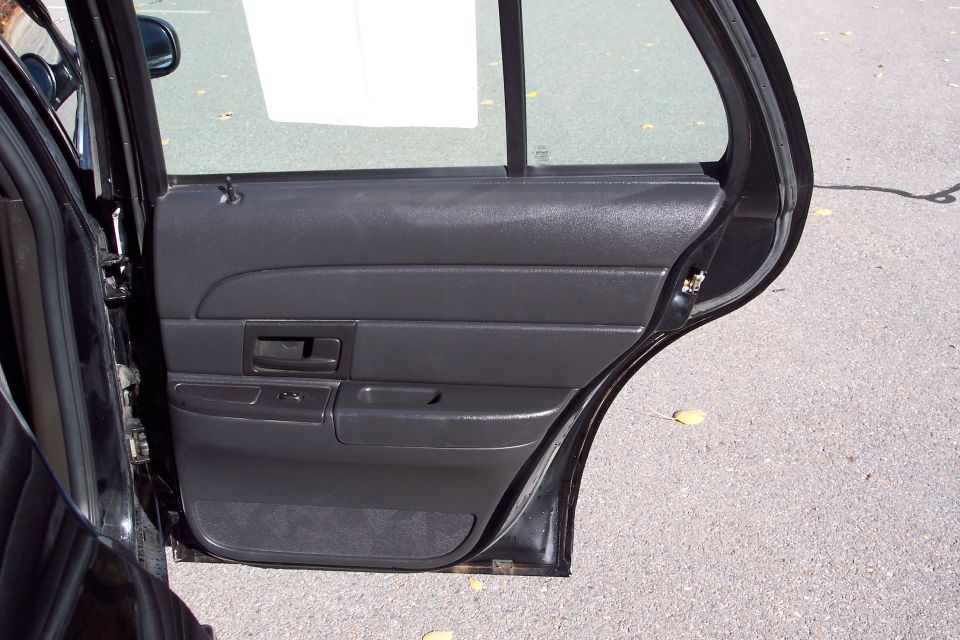 Interior of a black car door, showing the door panel and window frame