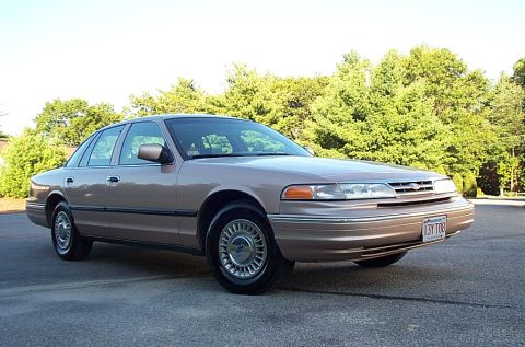 2001 Ford Crown Victoria - This 1998 Ford Crown Victoria has a tan exterior and is parked on an asphalt surface with trees in the background.