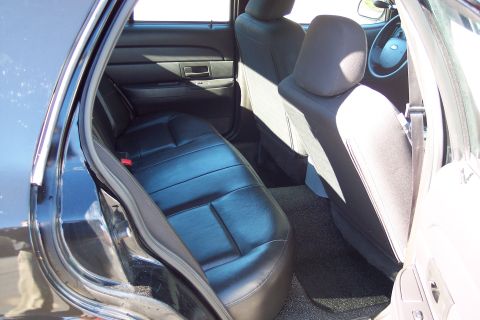 2001 Ford Crown Victoria - The interior of a police vehicle is shown, focusing on the rear seating area and the dashboard.