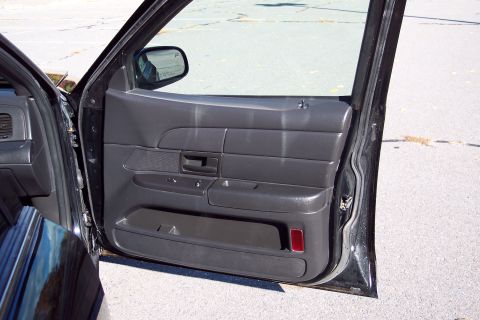 2001 Ford Crown Victoria - The interior door panel of a black car is shown with the door ajar.