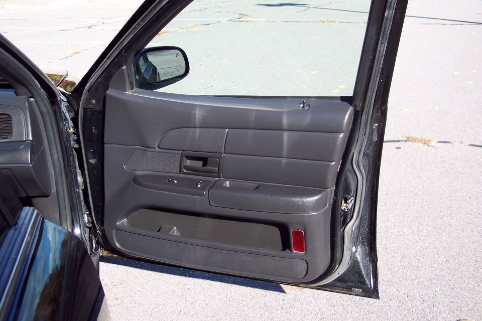 Black car interior door panel with a red reflector and a side mirror visible