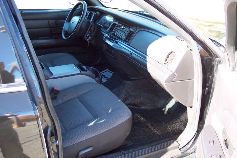 2001 Ford Crown Victoria - The interior of a 2001 Ford Crown Victoria police car is visible, the front seats, dashboard, and steering wheel.