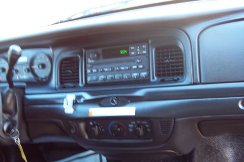 2001 Ford Crown Victoria - The dashboard of a police car features a radio, air vents, and climate controls.