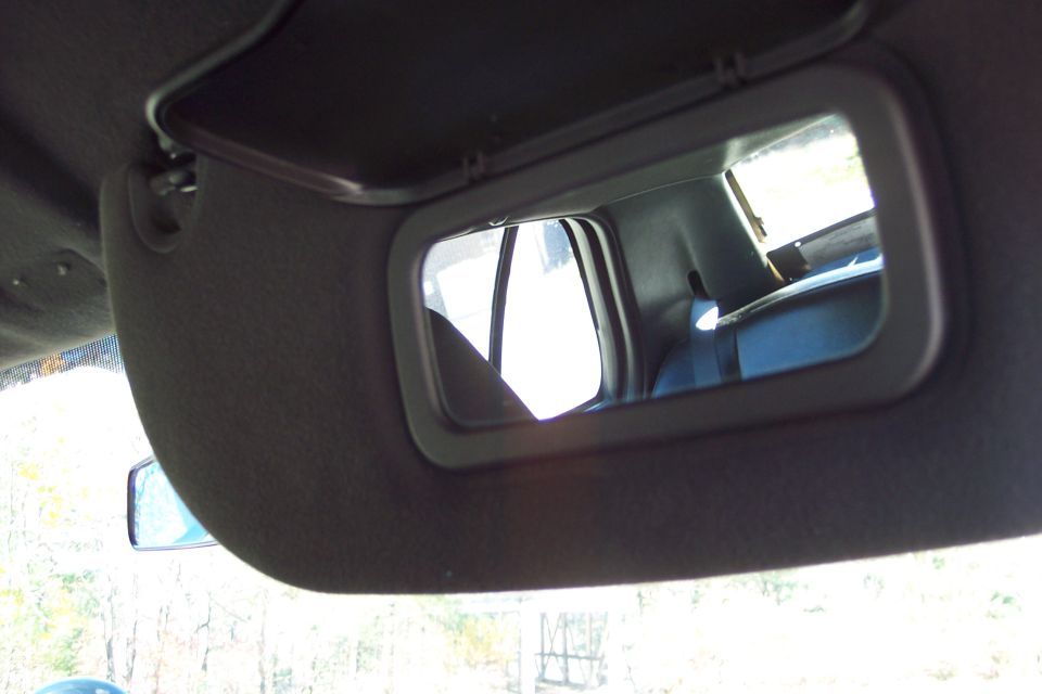 Car interior shot showing a visor mirror reflecting the back seat and window