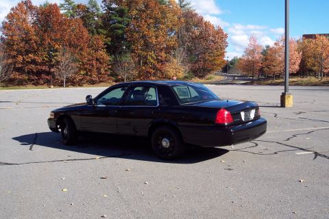 2001 Ford Crown Victoria - A black 2001 Ford Crown Victoria sedan is parked in an empty lot during autumn.