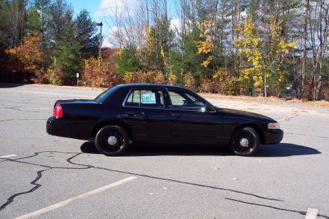 2001 Ford Crown Victoria - Side view of a black 2001 Ford Crown Victoria sedan parked in a lot during autumn.