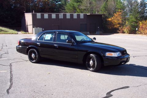 2001 Ford Crown Victoria - Black 2001 Ford Crown Victoria police car parked outdoors in front of a building.