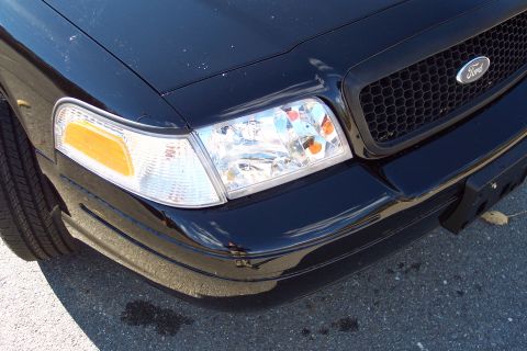 2001 Ford Crown Victoria - Front corner view of a black 2001 Ford Crown Victoria, showing the headlight and grille.