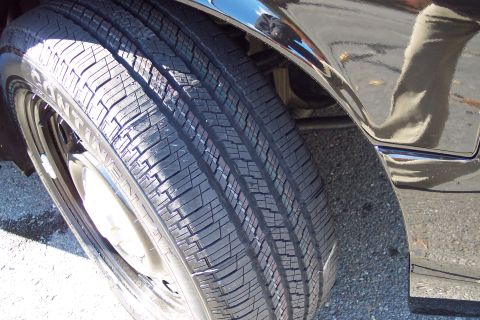 2001 Ford Crown Victoria - Close-up view of a tire and fender on a black vehicle.