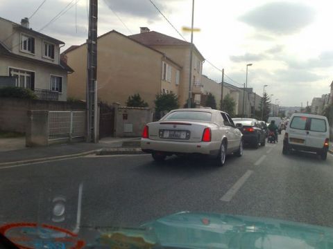 1991 Ford Crown Victoria - A white Cadillac sedan is seen from behind in a traffic jam on a cloudy day.