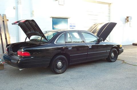 2001 Ford Crown Victoria - Black 2001 Ford Crown Victoria parked outside with both the trunk and hood open.