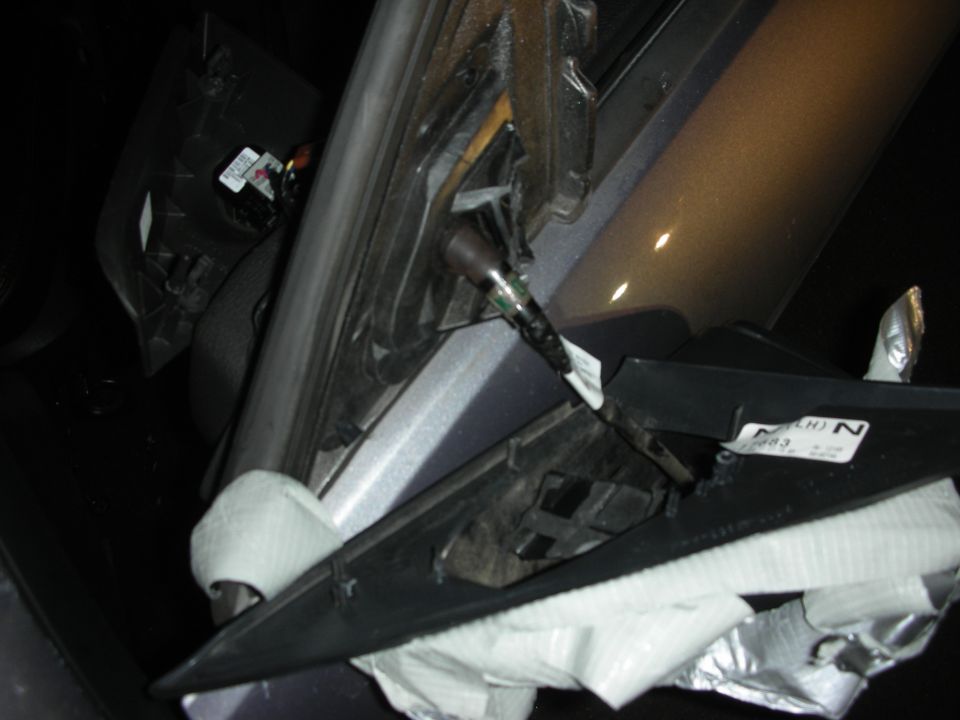 Close-up of a car's interior panel, torn and taped up, with wires exposed
