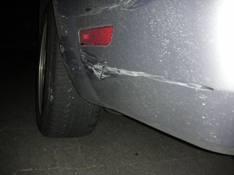 1998 Ford Crown Victoria - Close-up of a damaged rear bumper and tire on a gray vehicle.