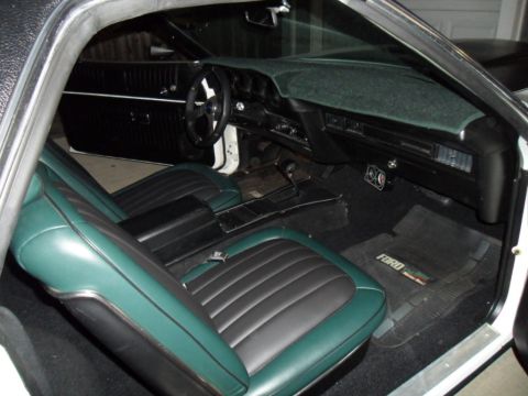 1973 Ford Ranchero - The interior of the vehicle features two-tone green and black seats and a black dashboard with a Ford-branded floor mat.