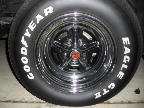1973 Ford Ranchero - A close-up view of a chrome wheel with a red and gold center cap, fitted with Goodyear Eagle GTI tires.