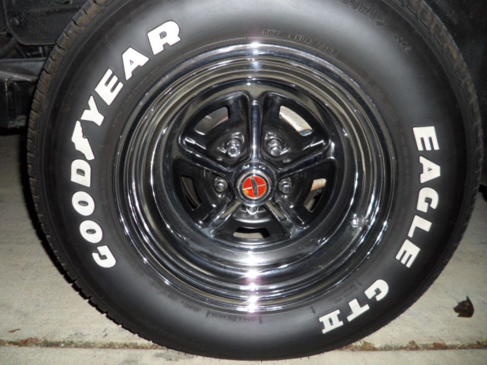 Close-up of a chrome wheel with a red and gold center cap and Goodyear Eagle GTI tires