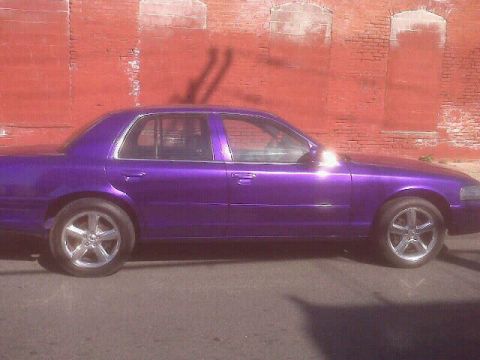 2003 Ford Crown Victoria - Side profile of a purple 2003 Ford Crown Victoria parked against a brick wall.