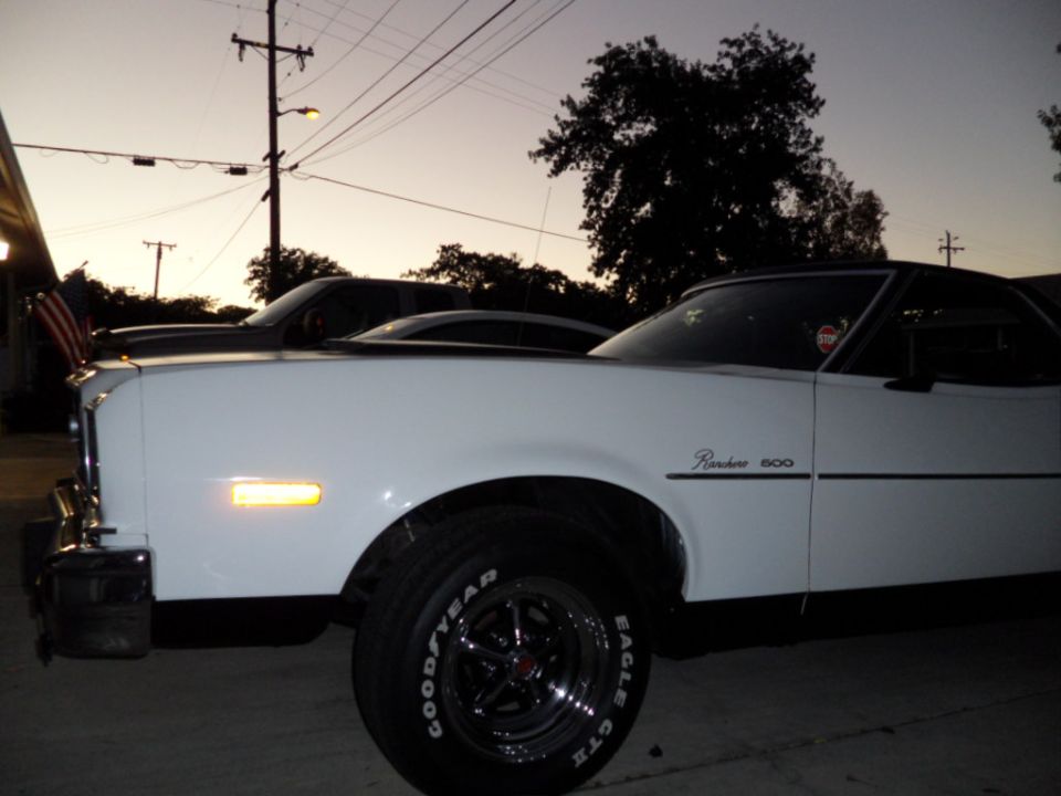 White Ford Ranchero 500 with black trim and Goodyear tires parked next to another car at dusk