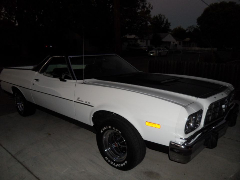 White 1973 Ford Ranchero with black hood stripe, parked outdoors at night