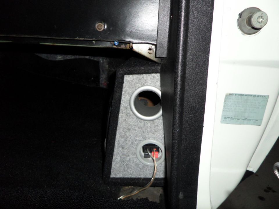 Custom speaker enclosure with two circular openings and wiring, mounted inside a vehicle