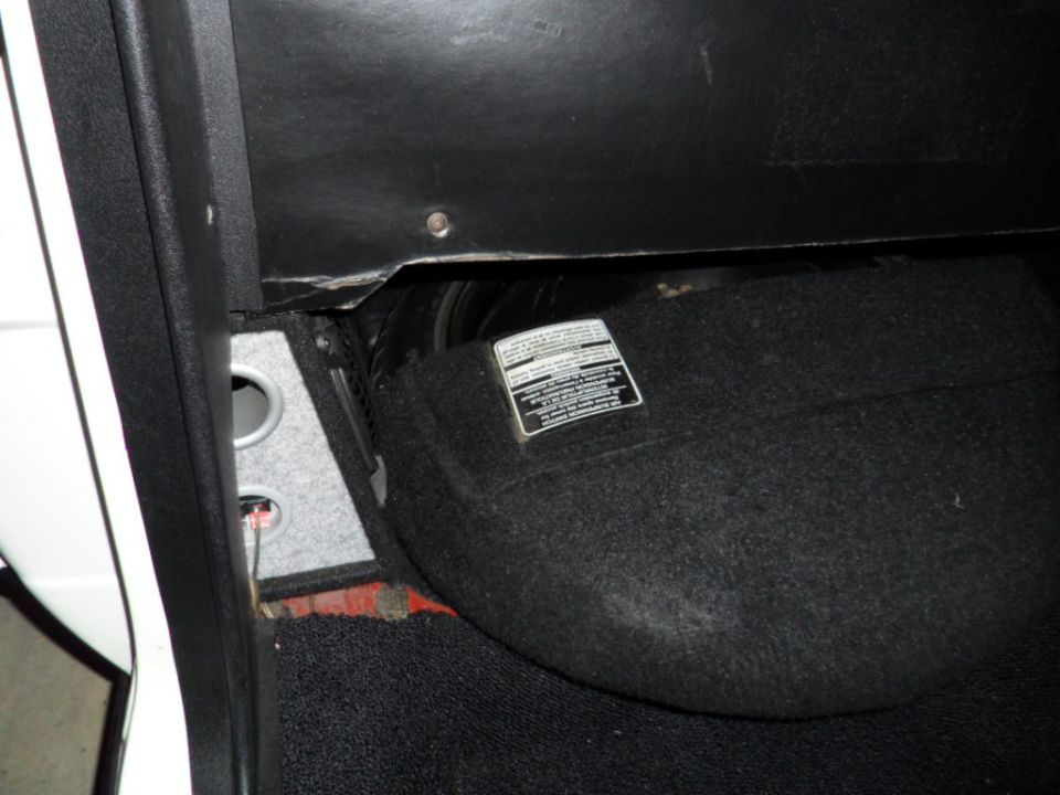 close-up of car's interior floor area with a sticker on a carpeted panel