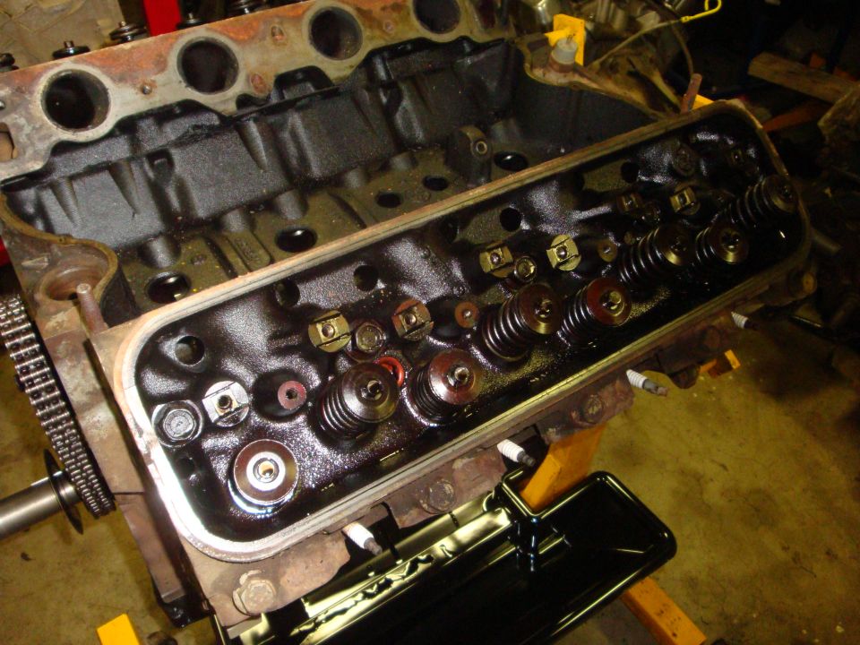 Engine cylinder head with valves and springs visible, covered in oil