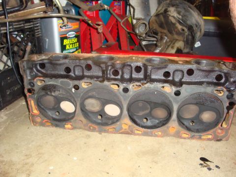 1989 Ford Bronco - Engine cylinder head shown in a workshop setting with various tools and supplies in the background.