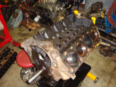1989 Ford Bronco - Engine block on a stand, with cylinders and crankshaft visible, in a workshop setting.