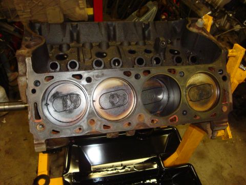 1989 Ford Bronco - Engine block with pistons removed, on an engine stand with an oil pan below.