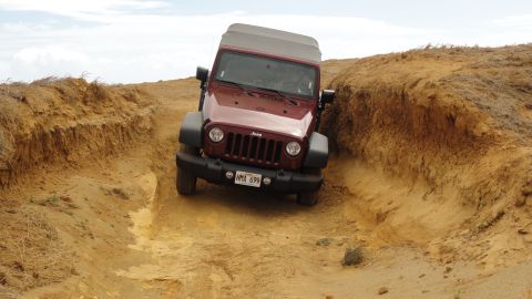 1989 Ford Bronco - A Jeep Wrangler navigates a narrow, sandy trail with eroded banks.