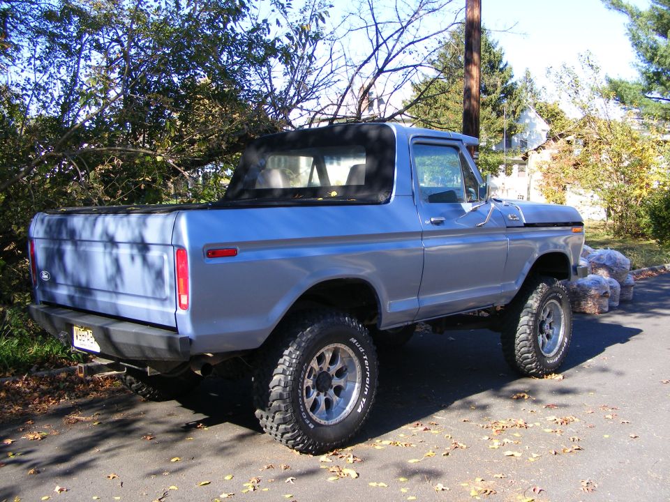 Blue Bronco with soft top, rear 3/4 view. Lifted suspension