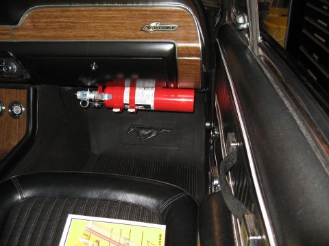 1968 Shelby GT500 - Fire extinguisher mounted in a 1968 Shelby GT500 interior, with a Mustang logo floor mat visible.
