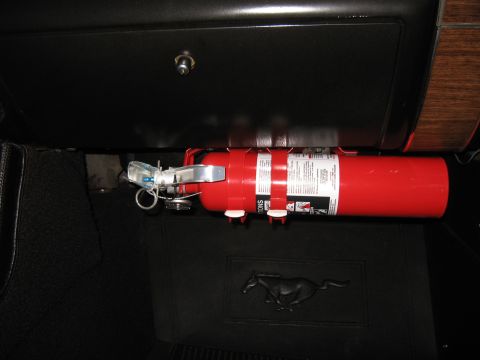 1968 Shelby GT500 - A red fire extinguisher is mounted under the dashboard of a 1968 Shelby GT500, with a Mustang logo floor mat visible.