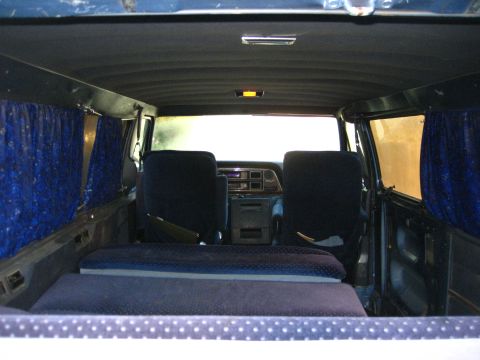 1989 Ford Bronco - Custom interior of a van, a bed platform and blue curtains.