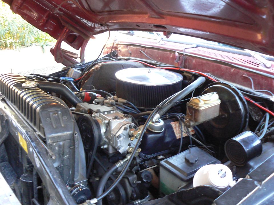 Engine bay of a red Ford truck, showing the V8 engine, radiator, and air filter