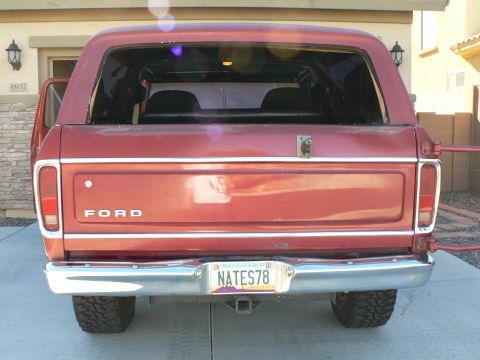 1978 Ford Bronco - The rear of a red Ford Bronco is shown, its tailgate and chrome bumper.