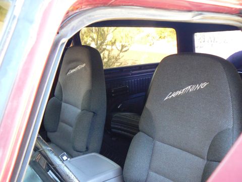 1978 Ford Bronco - Close-up of the interior showing the 'Lightning' embroidered seats and part of the steering wheel.